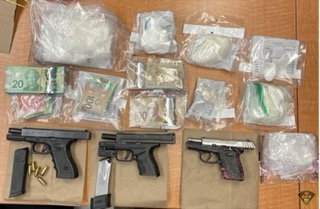 Three handguns and bundles of Canadian currency and packages of white powder.