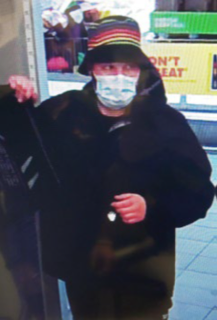 Person wearing a black coat, face mask, and patterned hat.