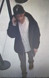 Person wearing a black jacket and white shirt, standing in a store.